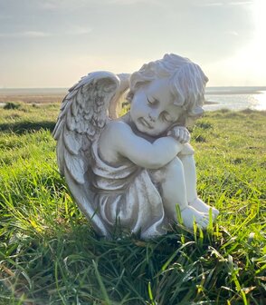 Engel beeldje in verweerd wit/grijs op een gedenkplek, decoratie voor graf of urnengraf
