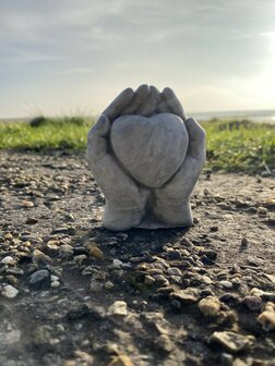 Handgemaakt herdenkbeeld handen met hart van beton