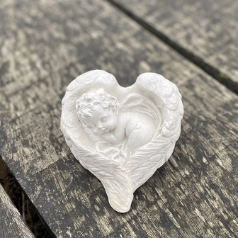 Handgemaakt herdenkingsbeeldje van een slapende baby engel, geborgen in een hart van vleugels