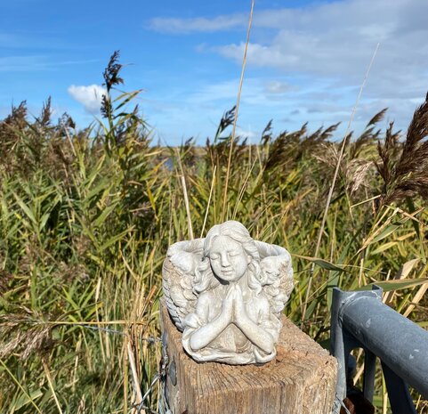 Biddende engel van polyresin in grijze steenlook, grafdecoratie en gedenkbeeld bij Allerheiligen.