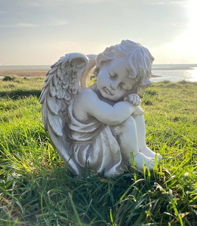 Engel beeldje in verweerd wit/grijs op een gedenkplek, decoratie voor graf of urnengraf