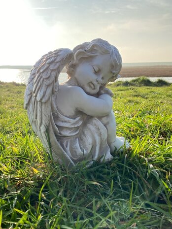 Verweerd engelenbeeldje van polyresin in zacht zonlicht, troostvolle gedenkdecoratie